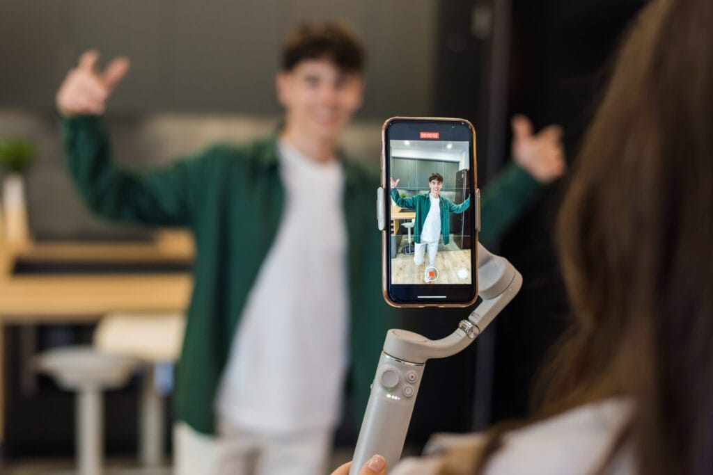 A person recording a young dancing man blogger influencer on smartphone on a stabiliser in a studio